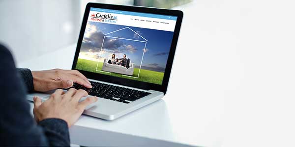 person looking at a laptop with Caniglia Heating & Cooling website