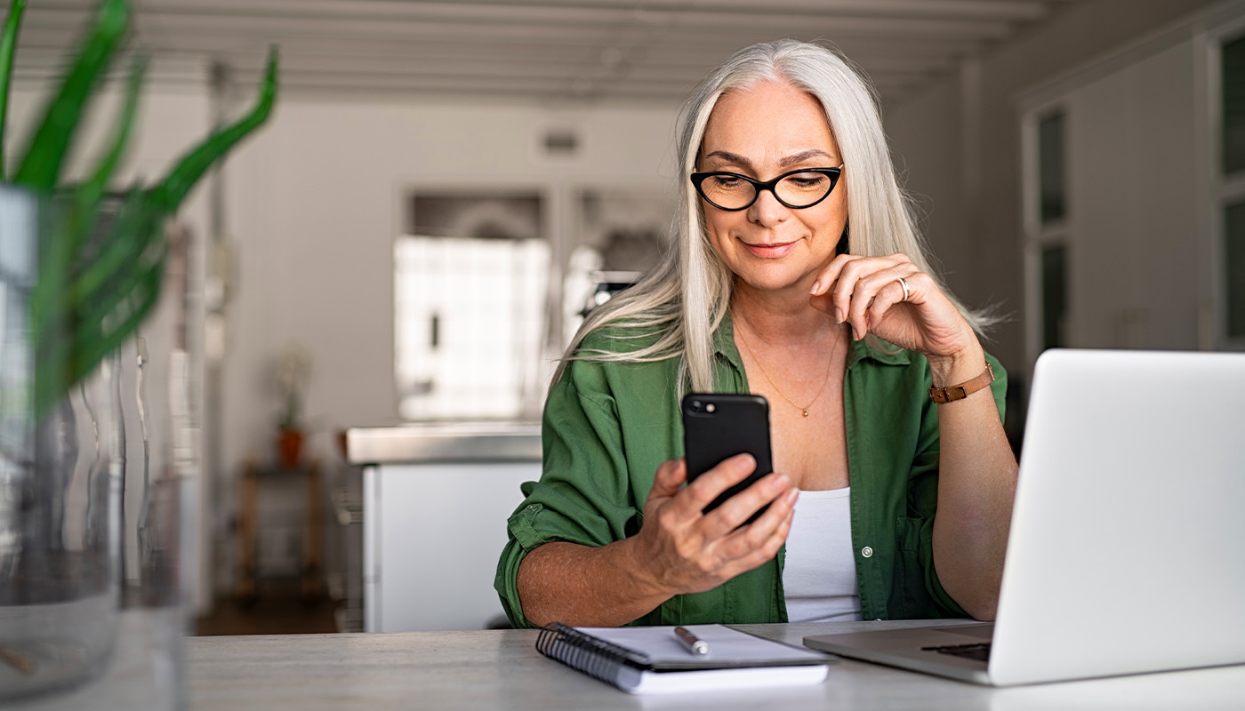 Woman checking phone while working at a computer