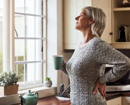 Woman looking out window while holding mug