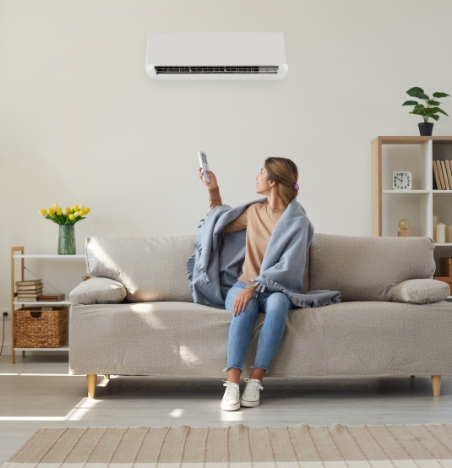 Woman in blanket changing her HVAC settings