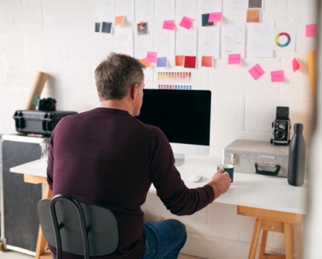 Man working at computer with sticky notes on his wall