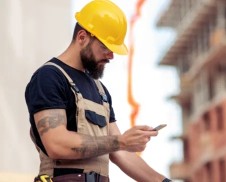 construction worker in hard hat checking his phone