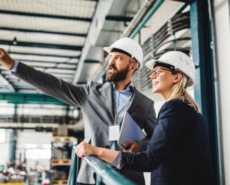Man and woman wearing hard hats in warehouse