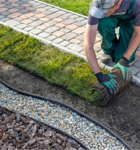 Man rolling out sod on new construction