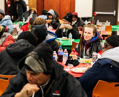 People eating at a food bank and watching camera