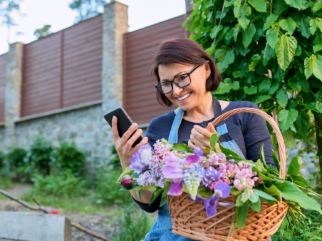 Woman on phone and carrying basket of flowers
