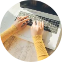 Female hands in yellow shirt typing on laptop